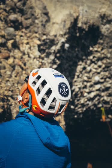 Escalador de espaldas, con casco, buscando el siguiente agarre